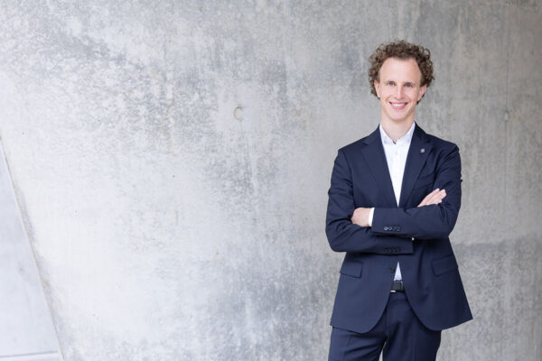 managerportrait von einem jungen unternehmer in der hafencity im hintergrund eine schöne sichtbetonwand